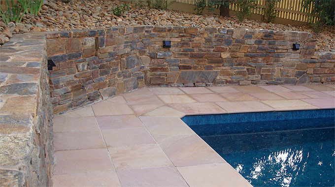 Pool landscaping in Camberwell with limestone coping, frameless glass and lush border planting.
