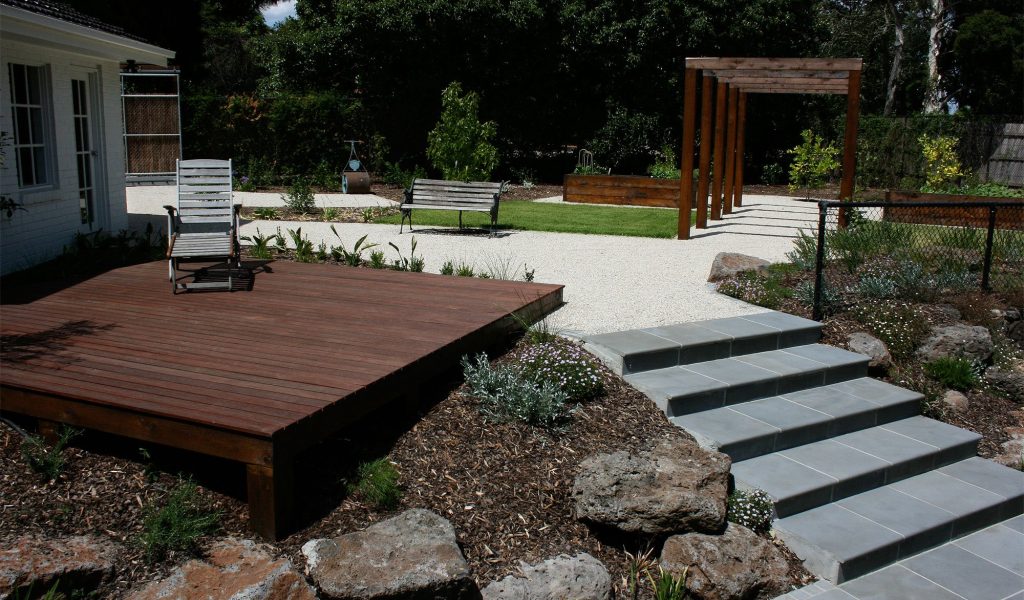 Modern landscaped backyard in Camberwell featuring timber decking, stone steps, gravel pathways and minimalist garden design