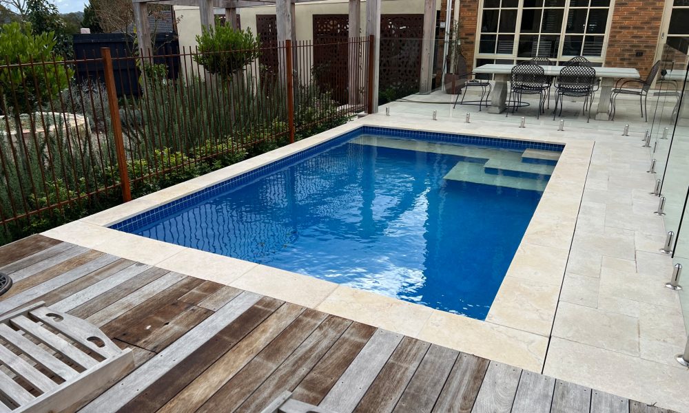 Pool surround near Camberwell Junction featuring travertine paving and a frameless glass pool fence